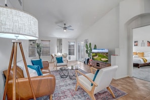 Living room with leather couch, accent chairs, 55" smart TV, and games.