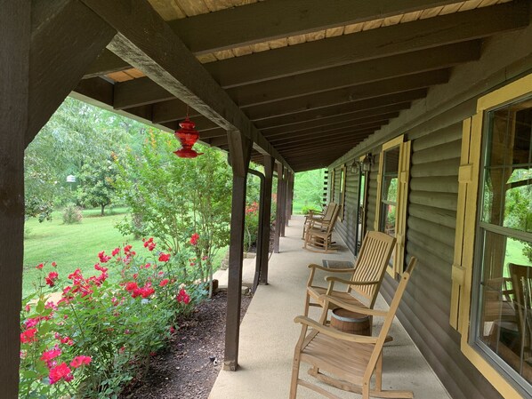 Welcome to the Lodge with porch lined with rocking chairs and roses