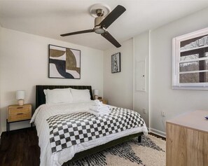 Queen bedroom featuring a comfort-controlled fan, flat screen TC, and convenient access to the bathroom just across the hall.