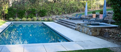 Heated pool and hot tub with lounge seating and umbrellas.