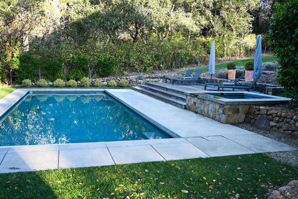 Heated pool and hot tub with lounge seating and umbrellas.