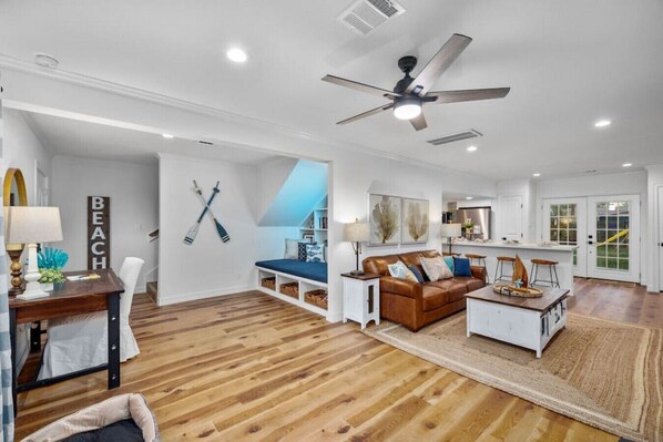 Overview of the downstairs living space showing the Nook, desk, living room and kitchen island.