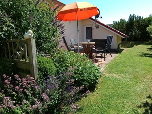 Sonnige Terrasse mit blühenden Sträuchern und Gehölzen