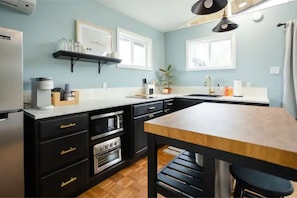 A fully equipped kitchen includes a fridge, microwave, toaster oven & cooktop.