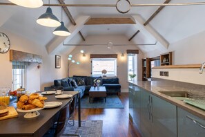 The kitchen and living room with a vaulted ceiling and beams at Exmoor Barn, Somerset