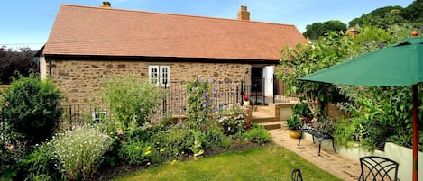 The garden with a dining table overlooking the exterior of Exmoor Barn, Somerset