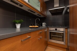 A modern kitchen with wooden cabinetry, a built-in oven, and practical appliances.
