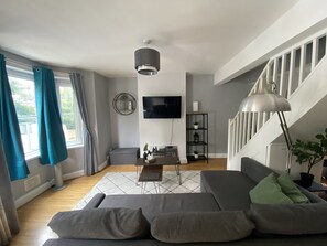 Living room with 43" smart TV, large L-shaped sofa that becomes a double bed