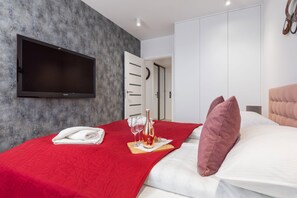 A cozy bedroom featuring a plush red blanket and a wall-mounted TV.
