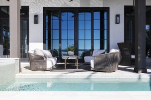 Patio seating - Looking at home over pool from the front with nice seating right by the pool and jacuzzi.