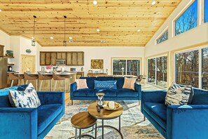 Bright, spacious, and filled with warmth. this stunning open-concept living area invites relaxation with its cozy seating, modern kitchen, and beautiful woodland views through floor-to-ceiling