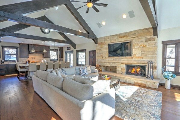 Open living and kitchen area with plush seating, fireplace, & vaulted ceilings 