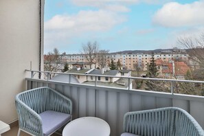 A balcony view with comfortable seating, overlooking the city and surrounding greenery.
