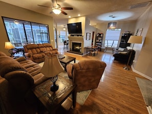Living room from bedroom hallway showing decorative fireplace and 65" smart TV