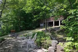 view up at the cottage from the flagstone patio from the lakefront. fire pit.