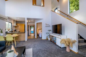 View looking towards the downstairs queen room, kitchen, dining, stairwell and upstairs room.