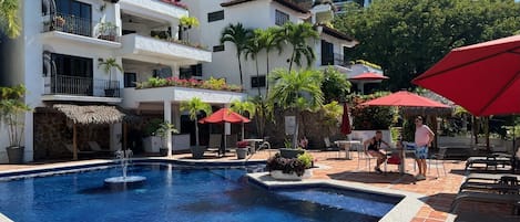 Main pool - heated with spacious deck, lounge chairs, tables and shaded palapas