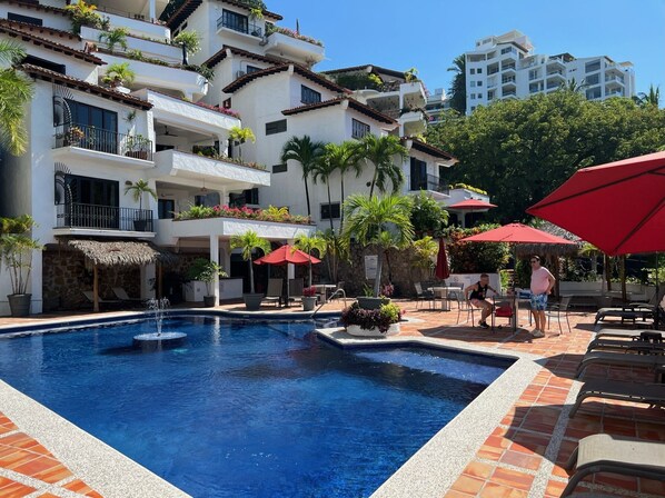 Main pool - heated with spacious deck, lounge chairs, tables and shaded palapas