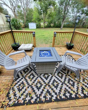 Outdoor deck with fire table and adirondack chairs. Opens to yard, has lanterns