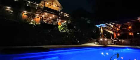 Night shot of Casa Cielo Jungle House from pool area.
