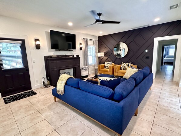 Living Room with large sofa, accent chairs, work desk and 65" TV. 