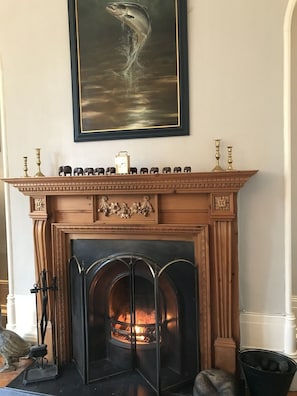 Fireplace with fish painting above and an elephant calendar on the mantelpiece