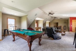 Rec room with regulation size pool table, foosball table, 75 inch smart TV, and table for games.