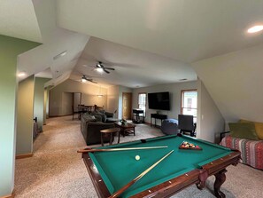 Second floor game room with sleeping space, large screen TV, Pool table, and high top table.
