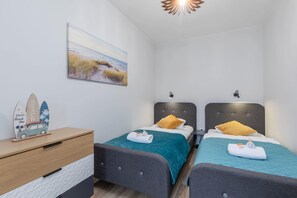 A bedroom with twin beds, nautical-themed decor, and soft lighting.
