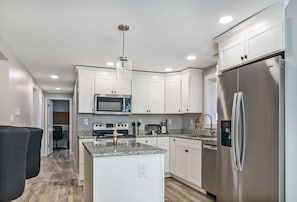 Kitchen with stainless steel appliances & granite, and full size fridge.