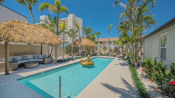 Newly resurfaced pool with two new lounging tiki huts with tropical landscaping