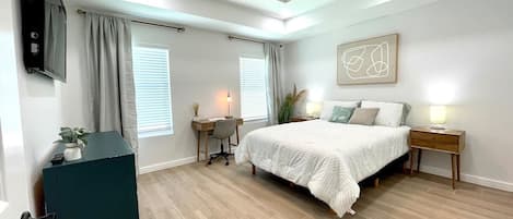 The tranquil and clean master bedroom with dedicated work space, dresser, and queen size bed. 