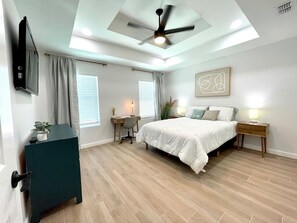 The tranquil and clean master bedroom with dedicated work space, dresser, and queen size bed. 