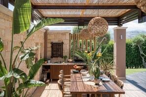 A fully equipped BBQ area with gas grill, mini fridge, kitchen, dishwasher and outdoor sink under a shaded pergola