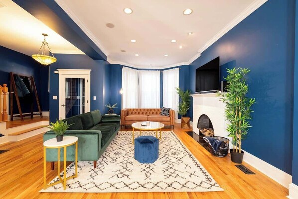 Main living room. 
Lush velvet couch, comfy leather couch, 65" smart TV, fireplace. Open floor plan next to dining area. Extra blankets. 