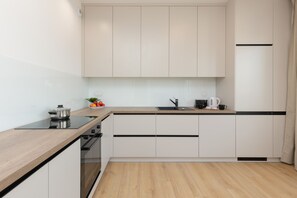 A modern kitchen with white cabinets, a wooden countertop, and built-in appliances.