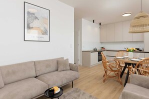 A spacious living and dining area with a gray sofa, a wooden table, and modern decor.
