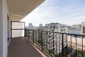 A balcony with a metal railing, offering a wide view of the surrounding apartment buildings.
