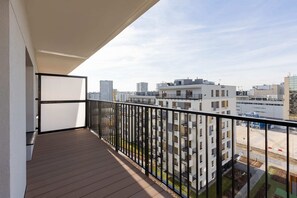 A balcony with a metal railing, offering a wide view of the surrounding apartment buildings.