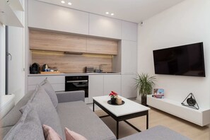 A living area with a sectional sofa, coffee table, and a mounted TV, designed in neutral tones.
