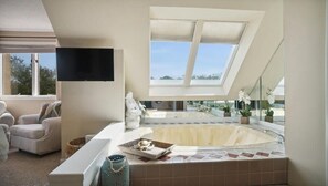 Oversized jetted bathtub with retractable shades and pivoting flat panel TV