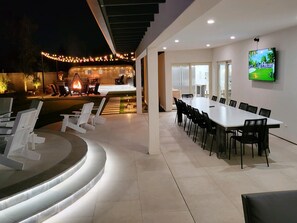 Covered patio with outdoor 17' marble dining table, seats 14 and TV