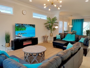 Large open-space living area with a high ceiling, 75" TV and in ceiling speakers