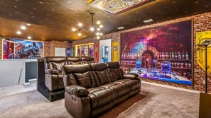 Magical-themed home theater with cozy recliners, vibrant murals, and warm lighting.