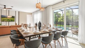 Bright dining area with modern decor, pool views, and natural light streaming in.