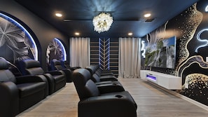 Luxury home theater with recliners, crystal chandelier, and modern design.
