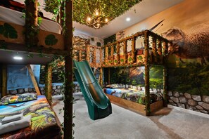 Dino-themed jungle room with slide and bunk beds—an adventure for all ages!