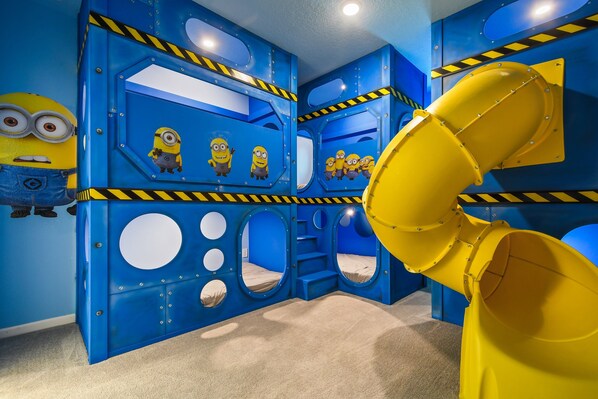 This playful room is designed with bright, cheerful Minion-themed decor and includes bunk beds and a slide for endless fun.