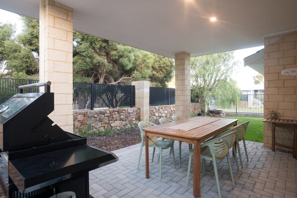 Enjoy alfresco meals in this covered outdoor space, complete with a large timber dining table and Webber BBQ