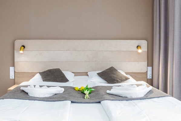 A modern bedroom with a double bed, crisp white bedding, and a neutral color palette.
